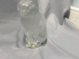 une figurine de chat posée sur une table près d'une fenêtre