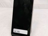 a black cell phone sitting on a stand on a white surface