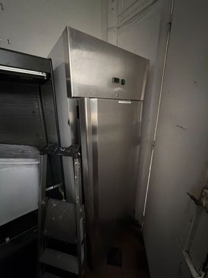 une photo d'une cuisine avec un réfrigérateur et une poubelle