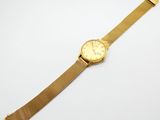une montre en or posée sur une surface blanche