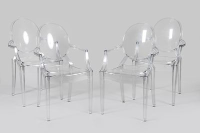 four clear plastic chairs sitting next to each other on a white surface