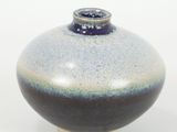 un vase bleu et blanc posé sur une surface blanche