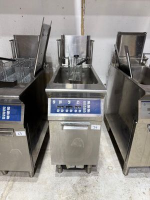 four commercial fryers are lined up in a row in a kitchen