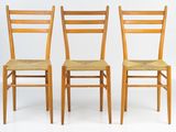 three wooden chairs with woven seats against a white background