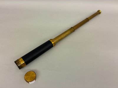 un vieux télescope avec une pièce de monnaie posée sur une surface blanche
