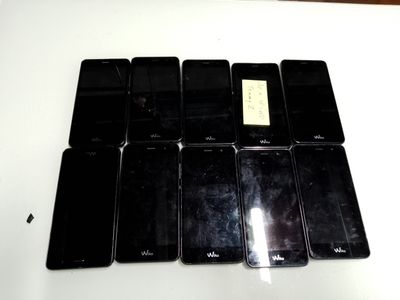 Plusieurs téléphones portables sont alignés sur une table blanche