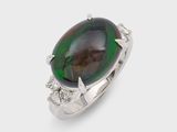 a close up of a ring with a green and black stone