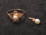 un gros plan d'une bague et d'une boucle d'oreille en perle posées sur une surface noire