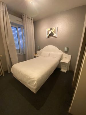 a white bed sitting in a bedroom next to a window