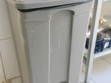 a white trash can sitting on a shelf in a kitchen