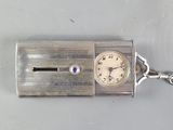 a silver clock that is on a chain on a table