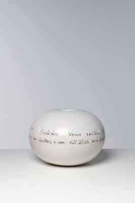 un vase blanc portant une inscription, posé sur une table
