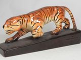 figurine représentant un tigre posée sur un socle en bois, sur fond blanc