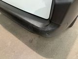 a close up of a black bumper on a white car