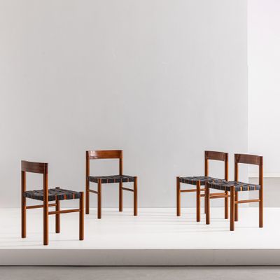 un ensemble de quatre chaises aux assises en cuir noir dans une pièce blanche
