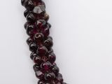 a close up of a strand of garnet beads on a white surface