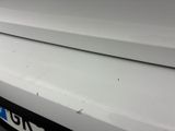 the front end of a white car with a dent in it ' s bumper