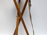 a small wooden stool with a leather seat on a white background
