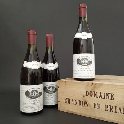 three bottles of wine are in a wooden box on a table