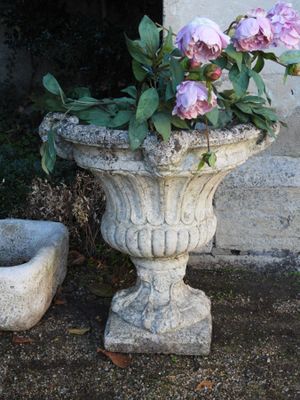 une jardinière en pierre remplie de fleurs roses, placée à côté d'un bol en pierre