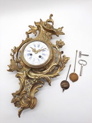 une horloge dorée accrochée au mur, à côté d'une clé