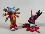 two figurines of clowns are standing next to each other on a white surface