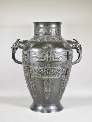 a silver vase that is sitting on a white surface