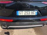 the rear end of a black car with a license plate on it