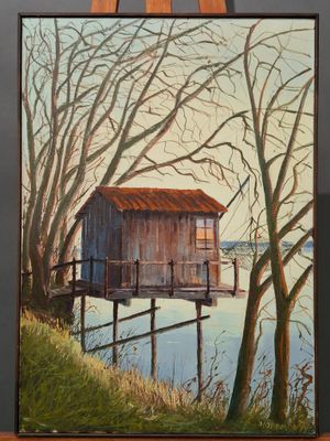 an oil painting of a house on a wooden easel by a body of water