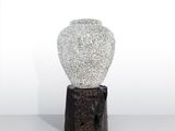 un vase blanc posé sur un socle en bois