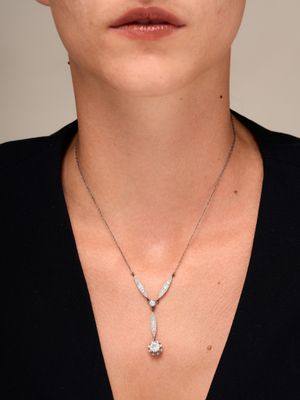 La femme porte un t-shirt noir et un collier de diamants autour du cou.