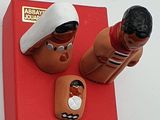 deux figurines représentant un homme et une femme assis sur une boîte rouge