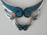 blue and silver necklace with wings on a white surface