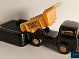 a black toy truck with a yellow dump truck in the back