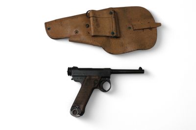 un vieux pistolet et un étui posés sur une surface blanche