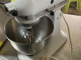 a white mixer sitting on a table next to a metal bowl
