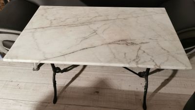 a white marble table with a black chair in the background