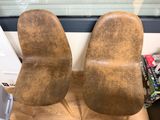 pair of brown leather chairs sitting on top of a wooden floor
