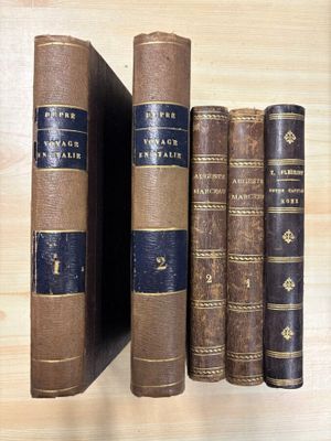 several old books are lined up on a shelf on a wooden surface