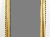 a gold framed mirror sitting on top of a wooden floor
