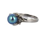 a close up of a ring with a blue pearl and diamonds