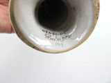 a hand holding a white vase with writing on it