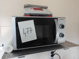 un micro-ondes posé sur une étagère, avec un bout de papier dessus