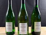 three bottles of wine sitting on top of a wooden table