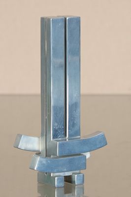 une sculpture en métal posée sur une table en verre avec un fond marron