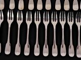 a lot of forks and spoons on a black table