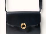 black leather handbag with a gold metal ring on the handle