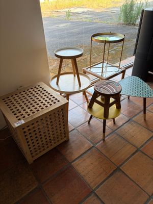 three tables and two stools in the corner of a room
