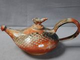 a brown and orange teapot with a bird on it