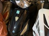 un homme debout à côté d'un scooter dans un garage